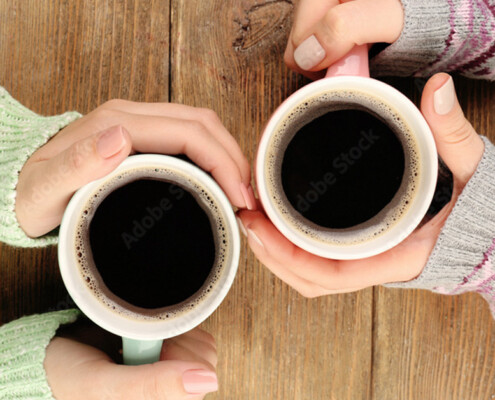 Close up of woman's hands wrapped around coffee cups