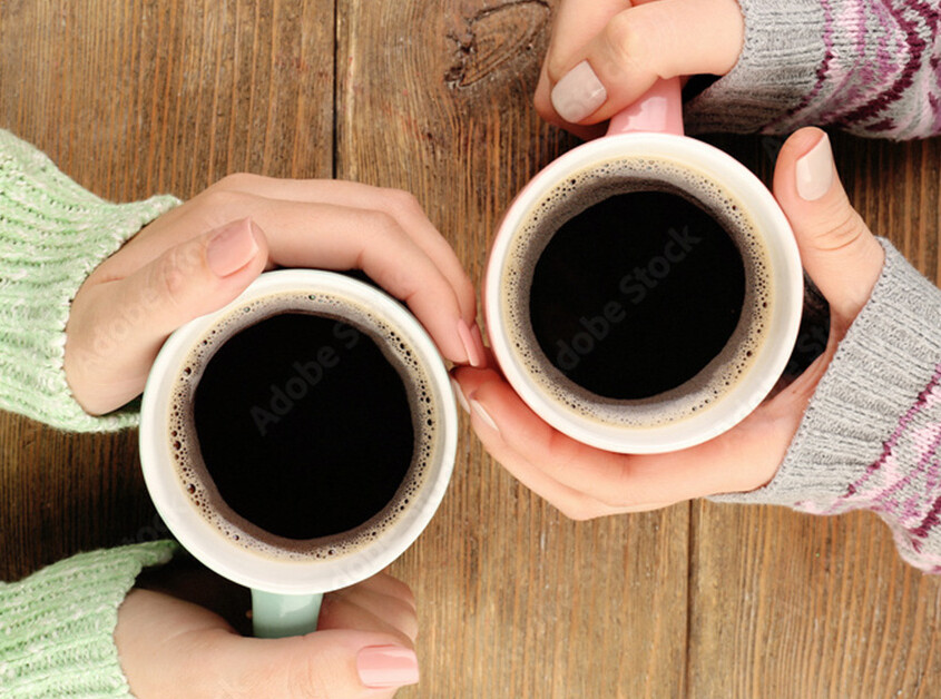 Close up of woman's hands wrapped around coffee cups