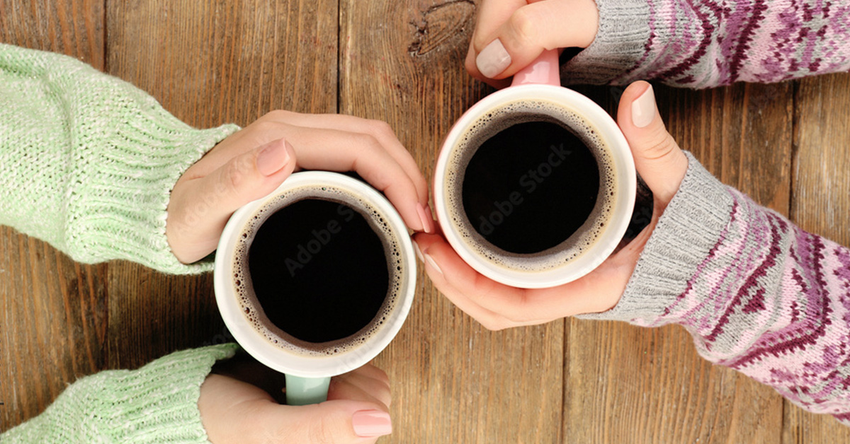 Close up of woman's hands wrapped around coffee cups