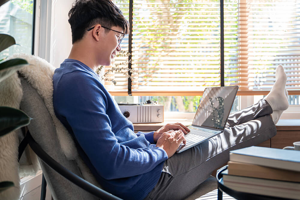 Young Asian man perusing information on his laptop