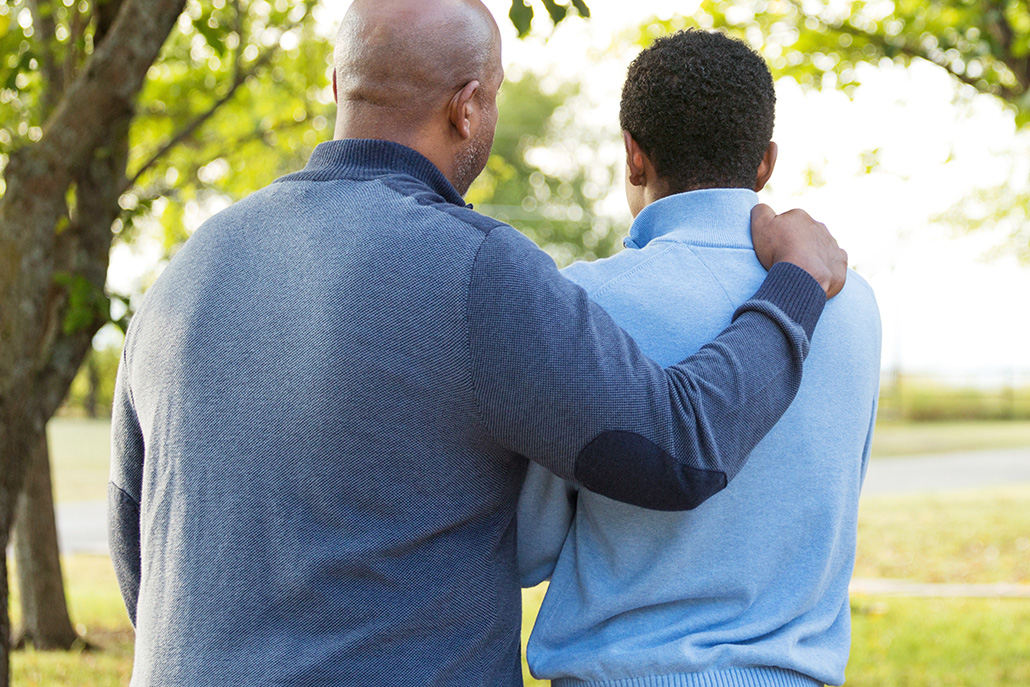 Father with arm around young adult son