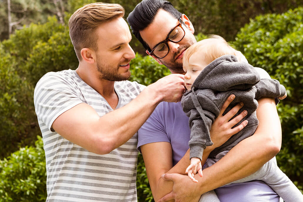 happy gay couple holding a small child