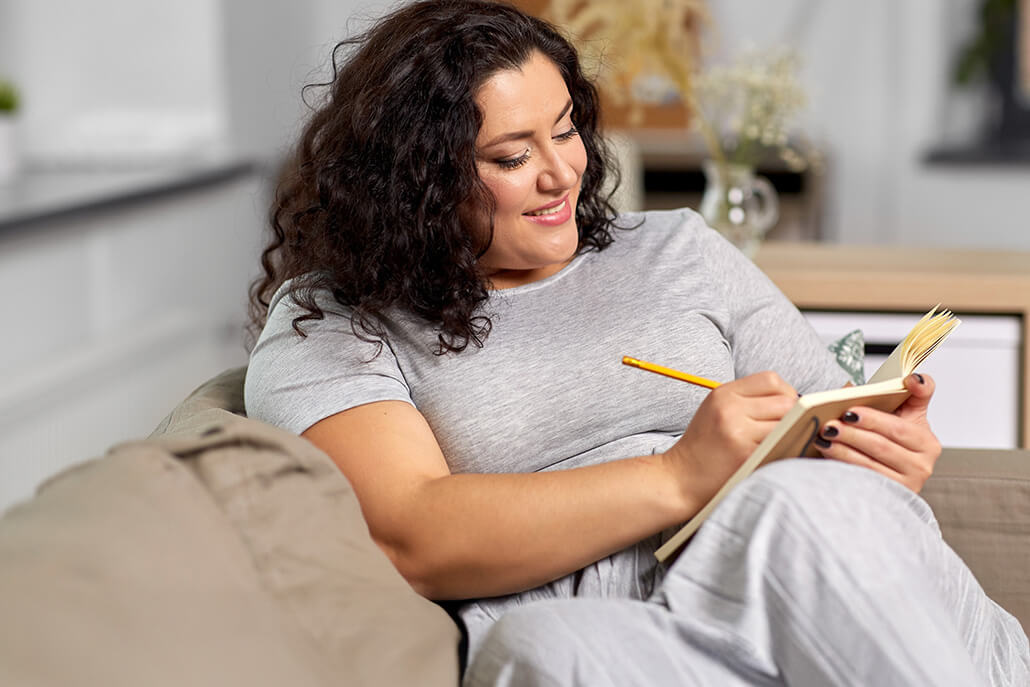 Plus size attractive woman writing in journal